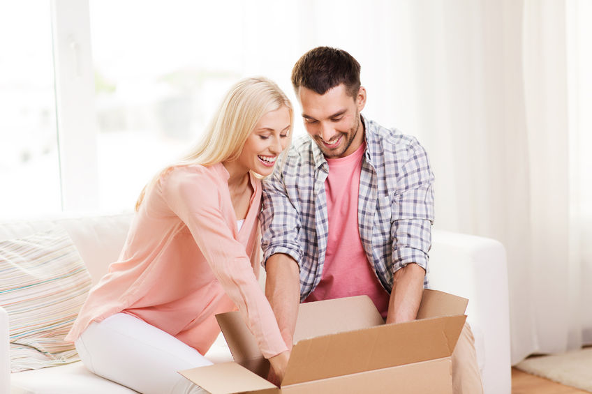 48902701 - happy couple opening cardboard box or parcel at home