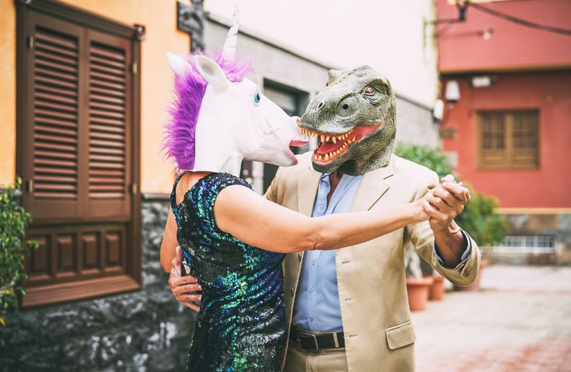 Crazy couple dancing and wearing dinosaur t-rex and unicorn mask